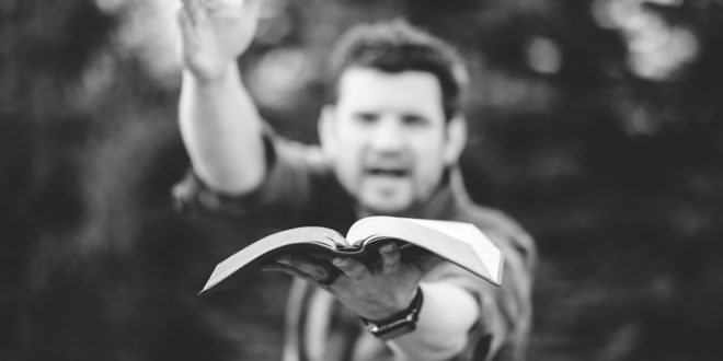 man preaching and holding up open Bible