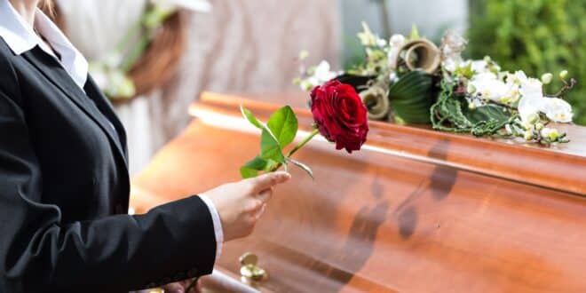 someone putting rose on coffin