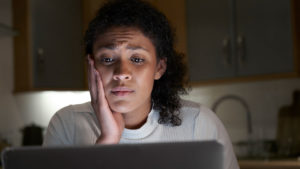 woman looking worried looping at laptop