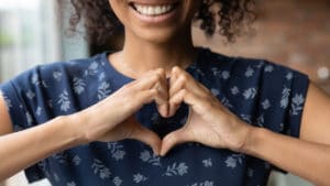 girl smiling with hands shaped like heart
