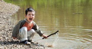boy playing with stick in stream