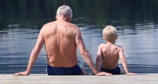 man and boy sitting on dock in twin trunks