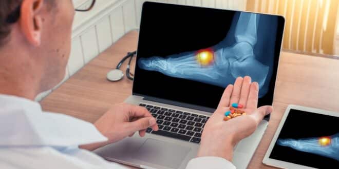 man looking at laptop and holding pills