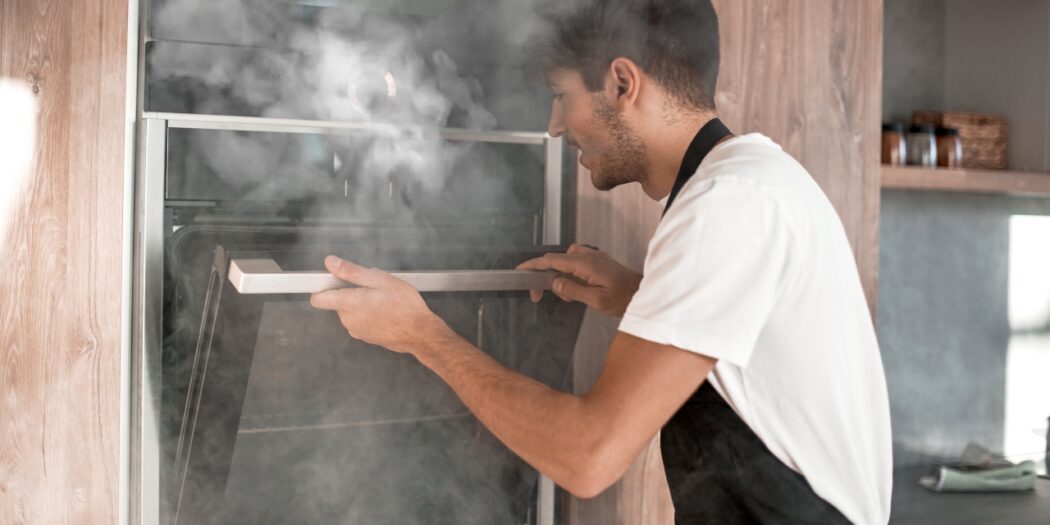 man peering in smoky oven