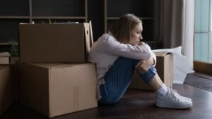 woman sitting on floor amidst boxes