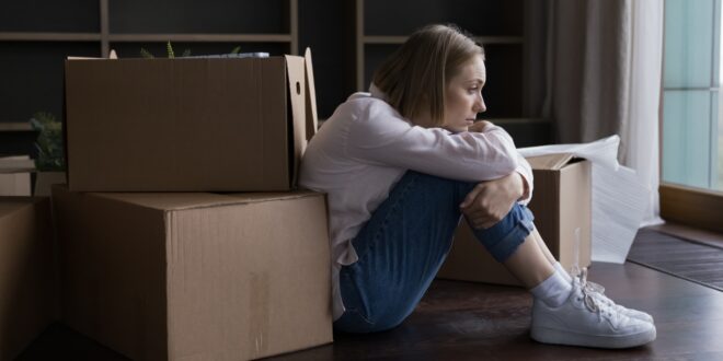 woman sitting on floor amidst boxes